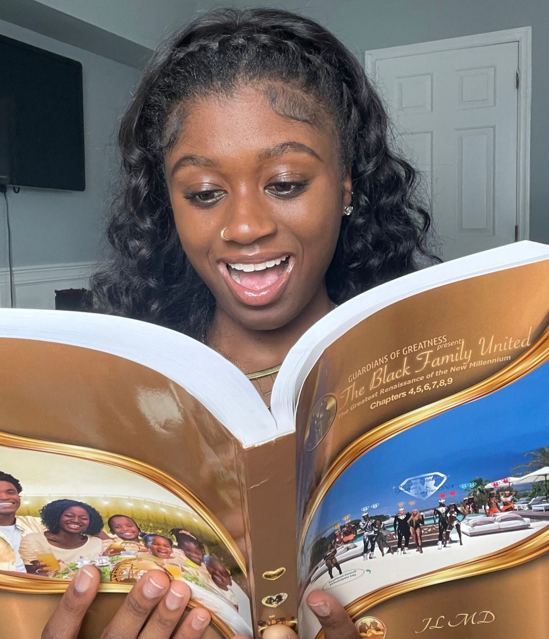 Beautiful Dark woman holding up the book The Black Family United - volume 3. Volume 3 contains chapters 4 to 9.